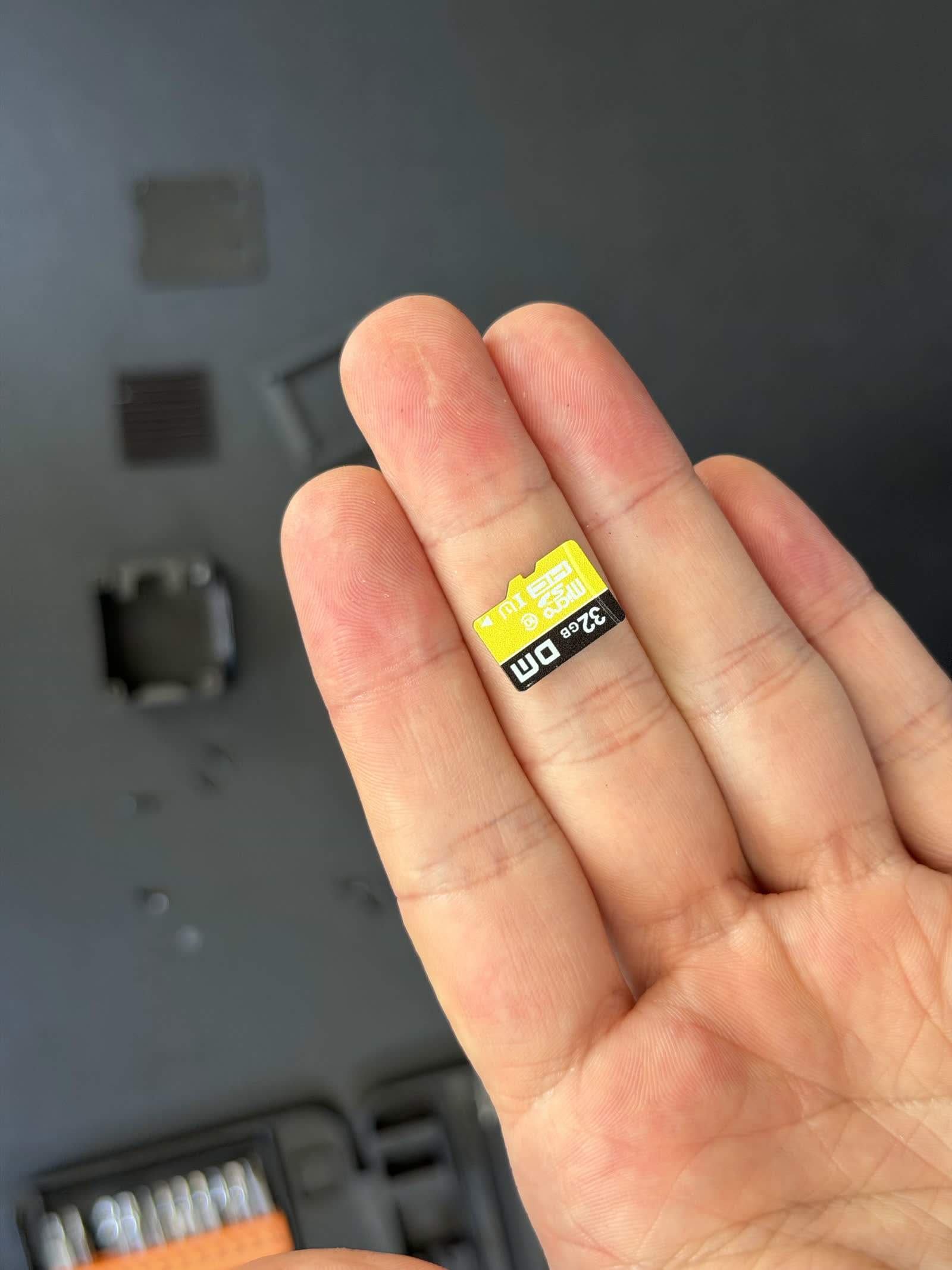 Macro photo of the generic DM-branded microSD shipped with the NanoKVM Full, next to a genuine SanDisk for contrast.