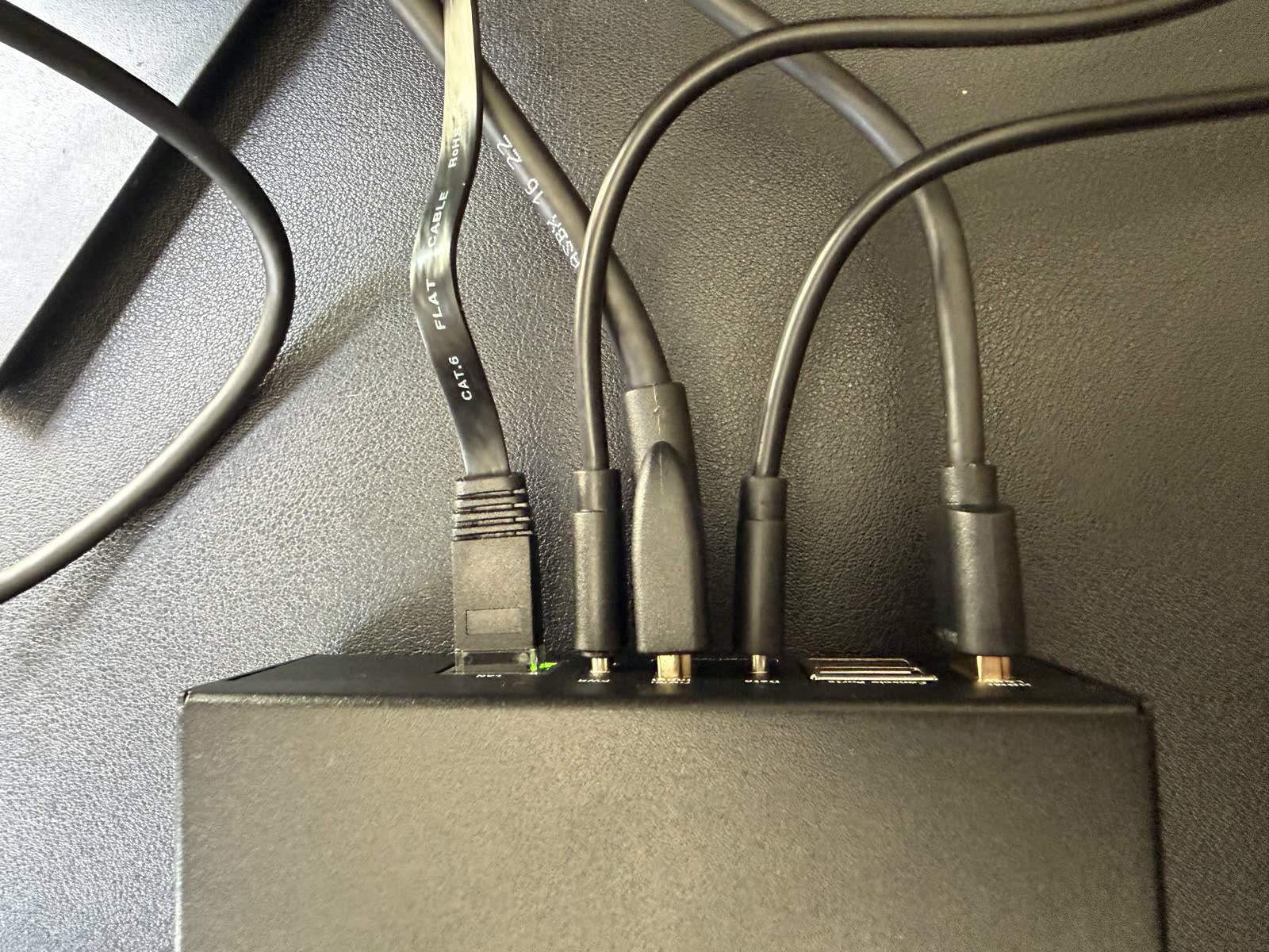 Rear of a mini PC with HDMI and USB cables running to a small KVM over IP device